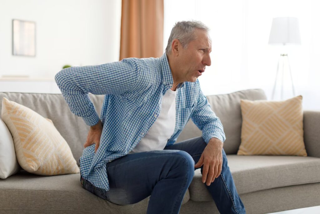Adults with Aches & Pains 1 mature man with side back pain sitting on couch at 2023 11 27 05 06 09 utc